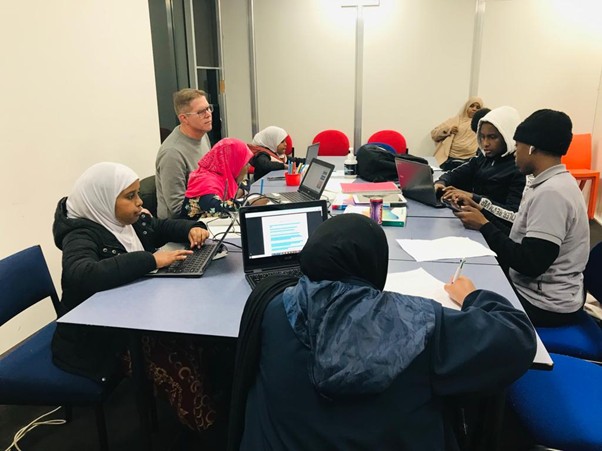 Homework Club students studying on laptops with a tutor at SWDA