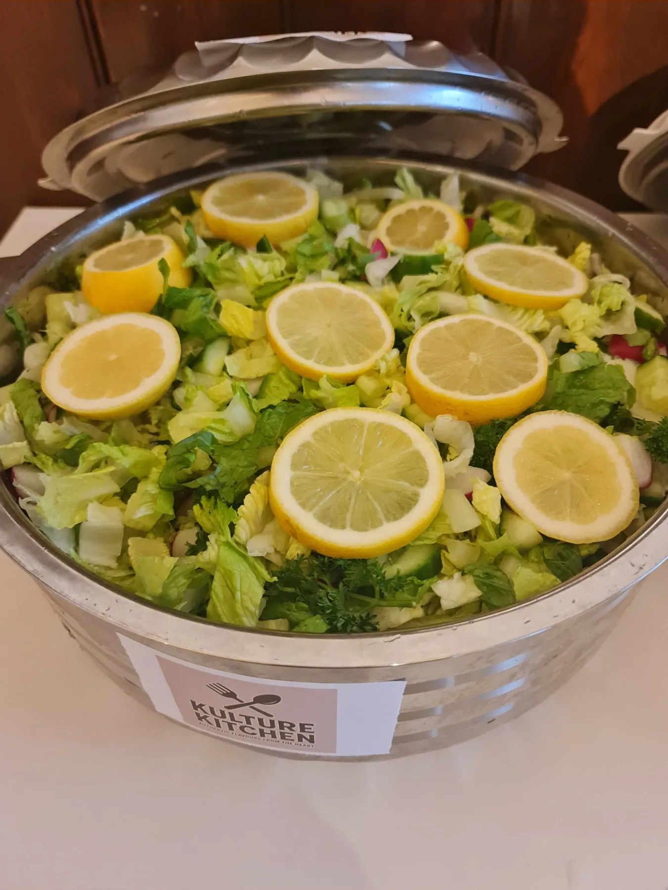 Large bowl of freshly prepared salad with lemon ready for community distribution