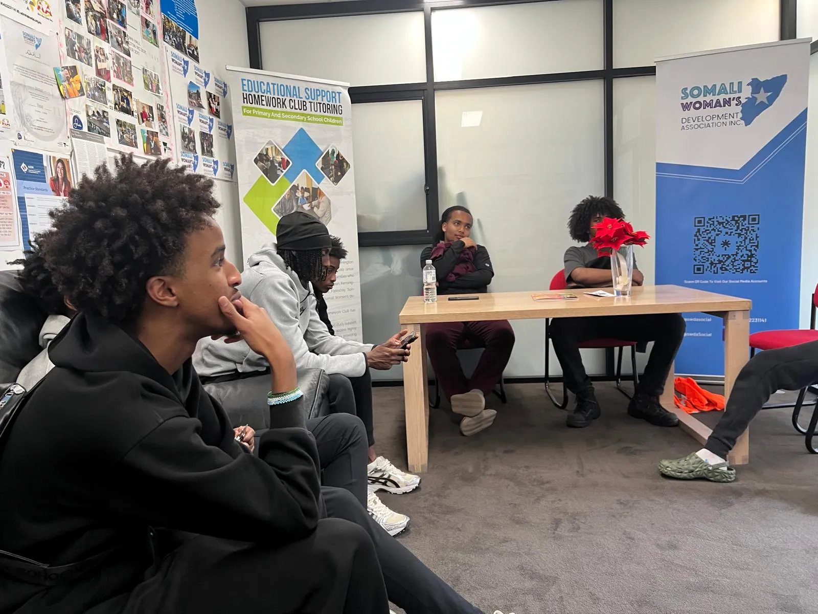 Young people at an SWDA Homework Club session beside the Educational Support tutoring banner