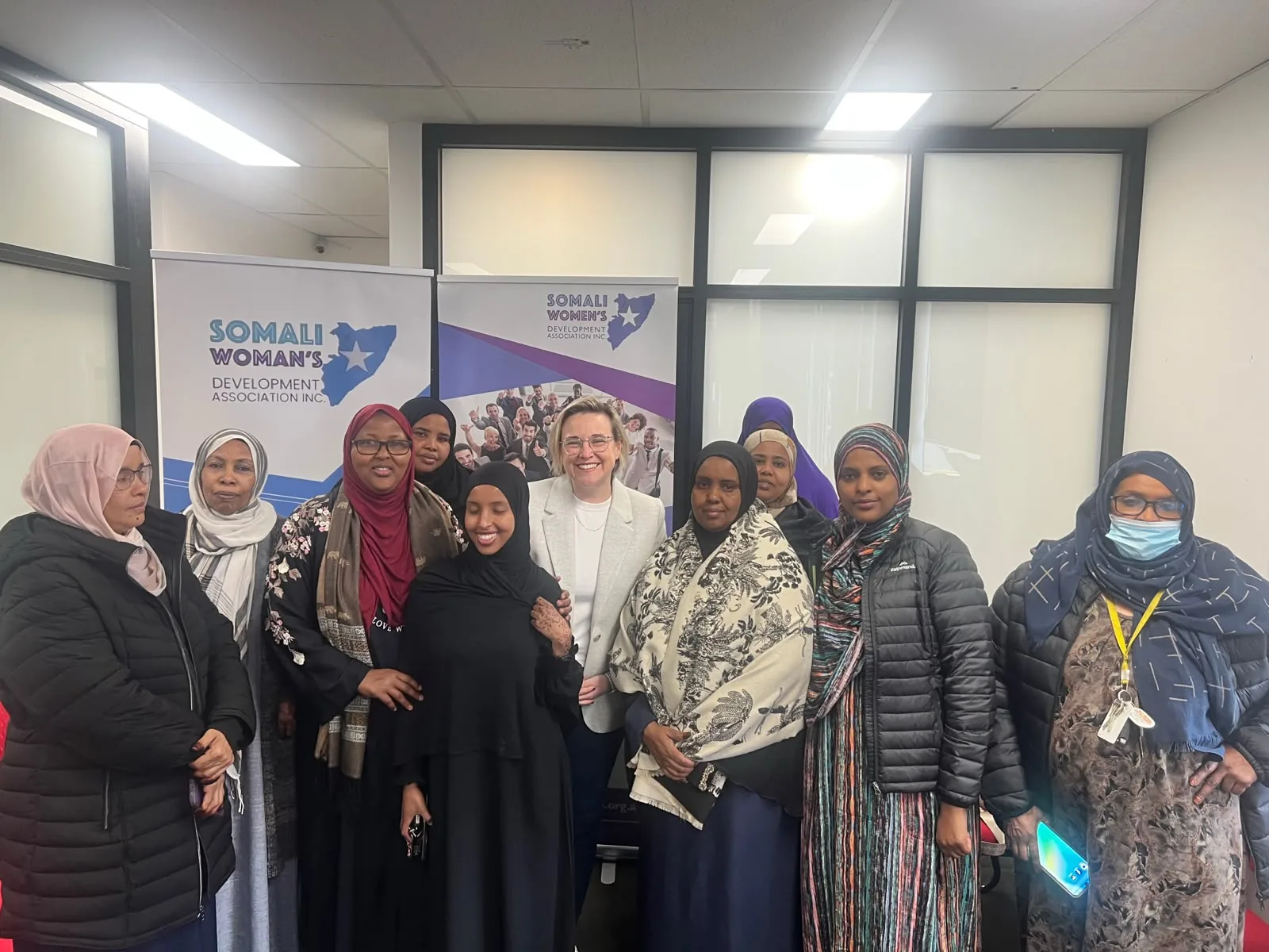 SWDA members and guests posing for a group photo in front of Somali Women's Development Association banners
