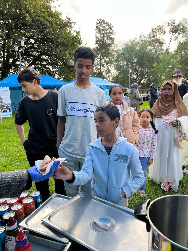SWDA volunteer serving hot food to children at a community food relief stall