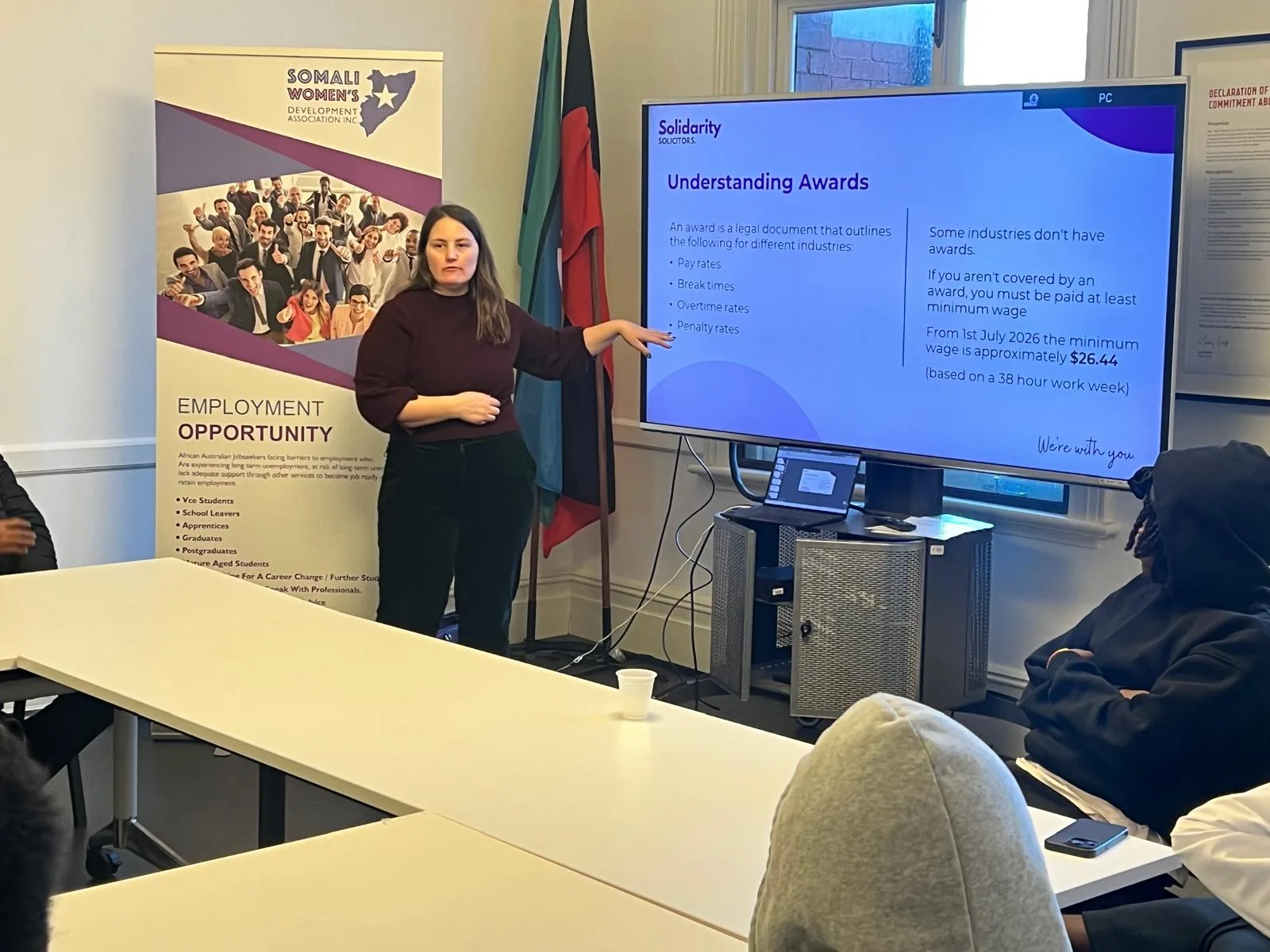 Employment workshop presenter speaking beside a screen during a session on awards and workplace rights