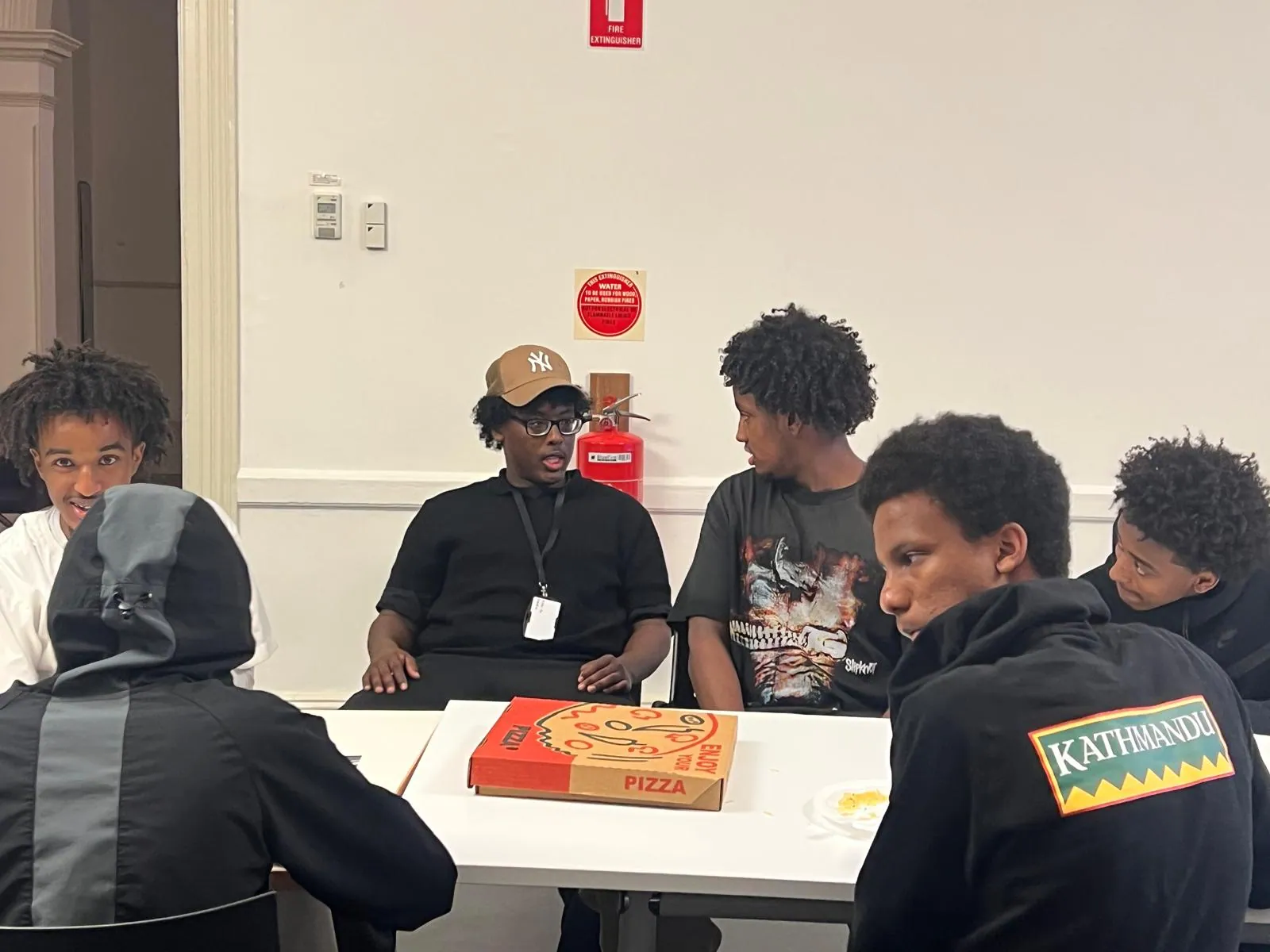 Young people sharing pizza and conversation at an SWDA youth program