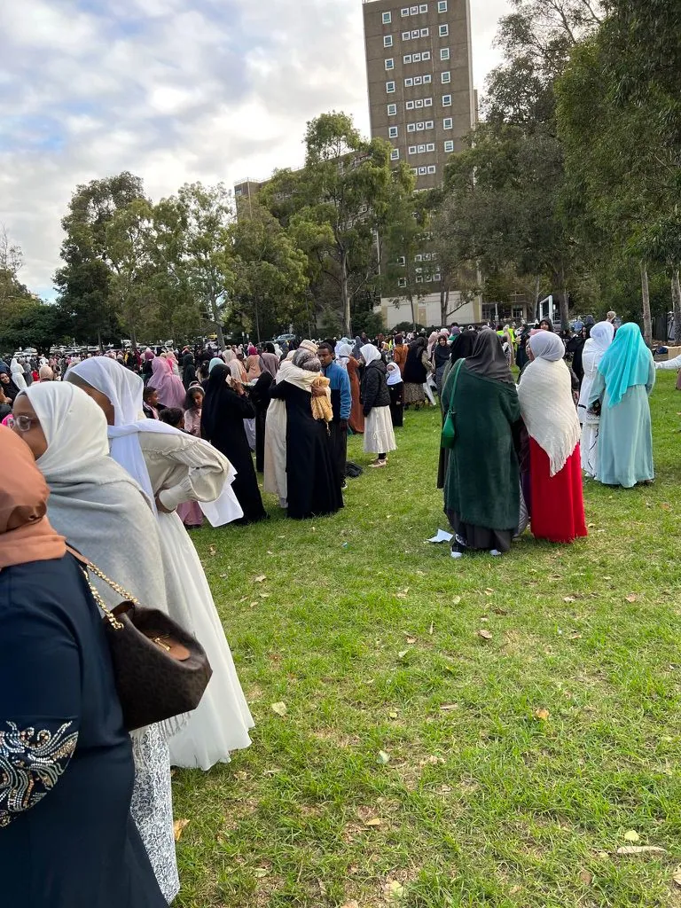 Community members greeting each other on the grass at the Multicultural Eid celebration