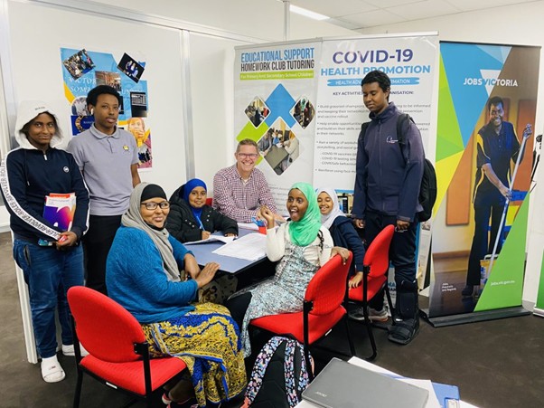 SWDA Homework Club students, tutors and staff together beside the Educational Support Homework Club tutoring banner
